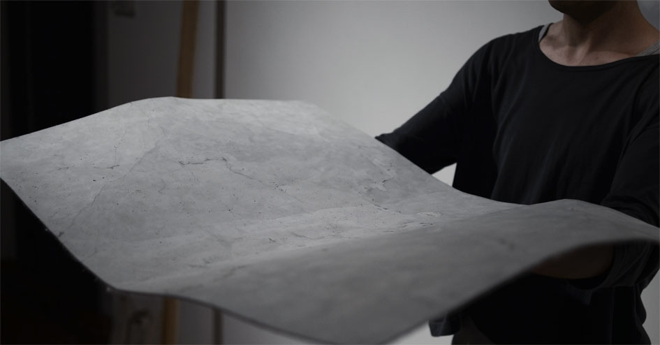 モルタルのマットを両手にのせて持ち上げている様子。ひび割れにそってたわんでいる。